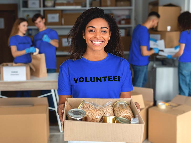 Young woman cheerfully holding a box of dry goods at a warehouse
