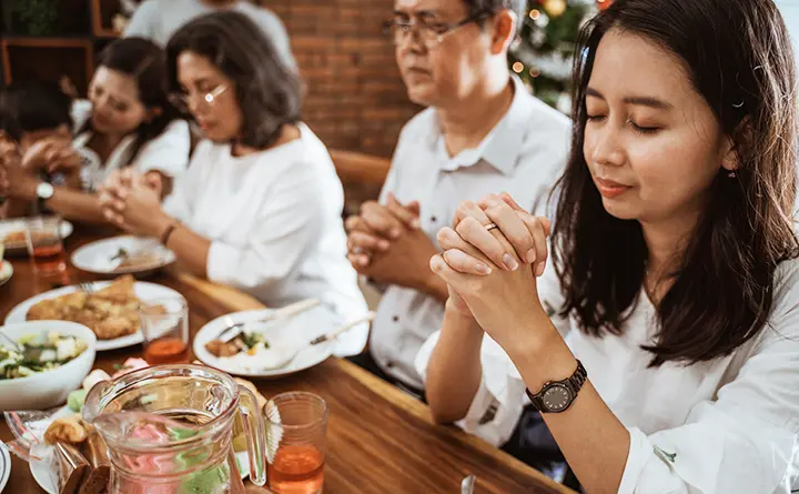 A close-knit Latino family sits and prays together before a meal