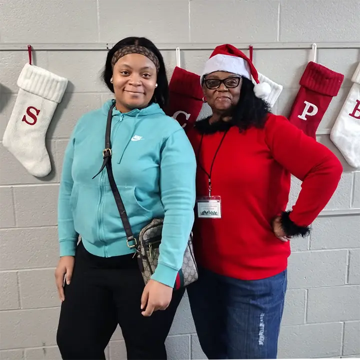 A volunteer and a young woman stand together at the 2025 Toy Give-A-Way